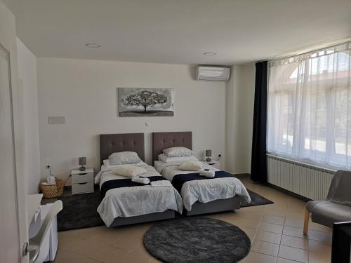 a bedroom with two beds and a tree on the wall at Marko Airport Rooms in Velika Gorica