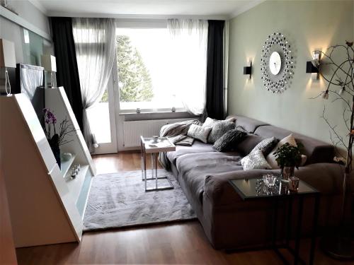 ein Wohnzimmer mit einem braunen Sofa und einem großen Fenster in der Unterkunft Großdorf Appartement En Vogue im Hahnenklee, Harz in Hahnenklee-Bockswiese