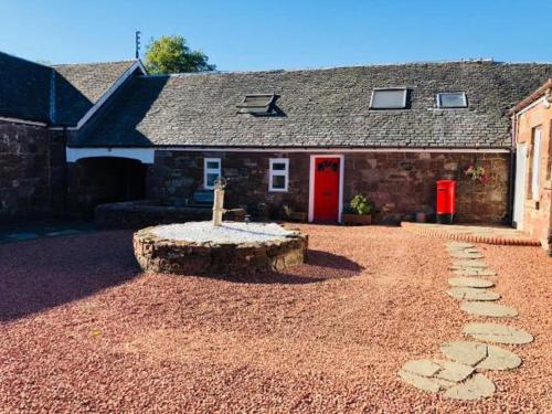 a stone house with a red door and a stone bench at Whiteley’s Cottages studio in Dumbarton