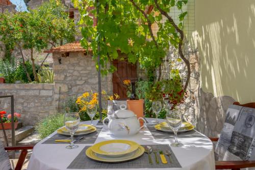 a table with plates and wine glasses on it at Mediterranean terrace apartment with Bikes & SUP in Skradin