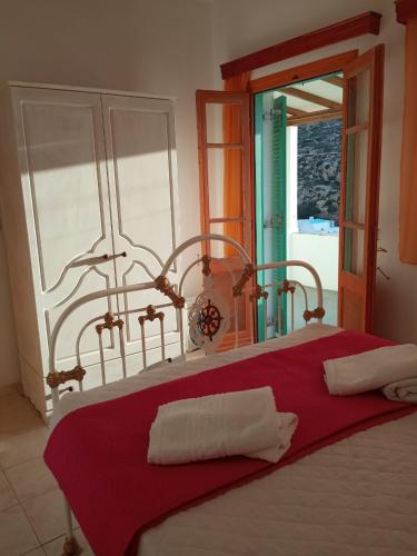 a bed with a red blanket and a window at Kokagia House in Cherronisos