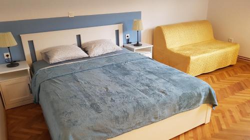 ein Schlafzimmer mit einem großen Bett und einem gelben Stuhl in der Unterkunft Apartma Lahinja in Gradac
