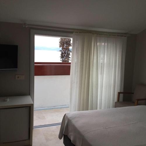 a bedroom with a bed and a large window at Teos Lodge Pansiyon in Siğacık
