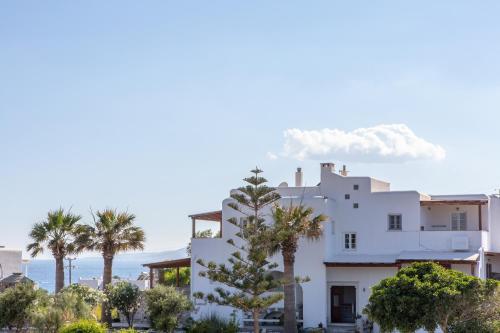 a white house with palm trees in front of it at Thea Suites Naxos in Agios Prokopios