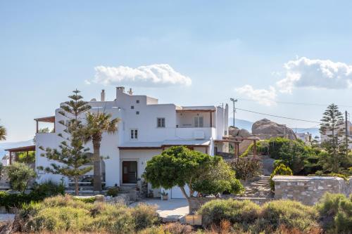 a white house with trees in front of it at Thea Suites Naxos in Agios Prokopios