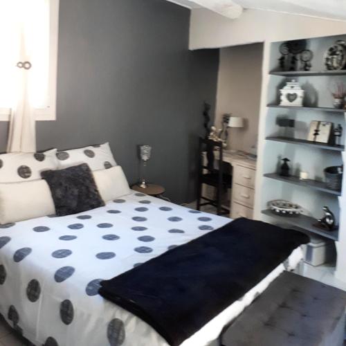 a bedroom with a bed with a black and white comforter at Les MIRABELLES chambres d'hôtes in Sisteron