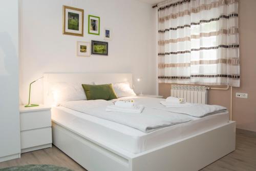 1 cama blanca grande en una habitación con ventana en Apartment Vidus Wine Estate, en Podnanos