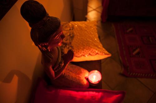 a doll sitting next to a lamp with a candle at Attico rooms in Giardini Naxos
