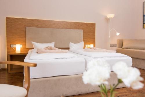 two white beds in a room with a couch at T3 Hotel Cityloft in Mönchengladbach
