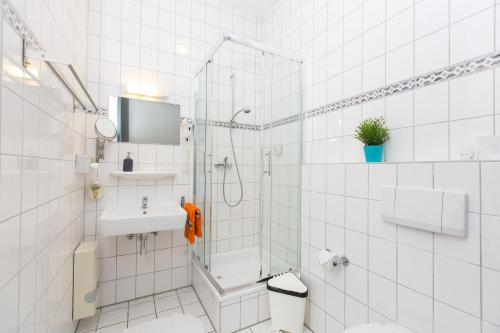 ein weißes Bad mit einer Dusche und einem Waschbecken in der Unterkunft T3 Hotel Cityloft in Mönchengladbach