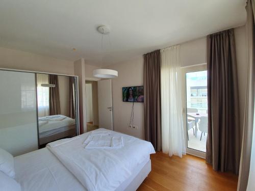 a bedroom with a white bed and a balcony at Apartments Menuet in Budva