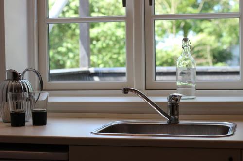 a kitchen sink with a bottle and a window at Hedegaard Holiday Apartments in Give