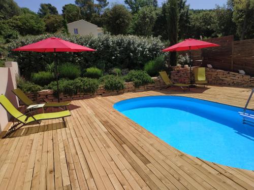 una piscina con 2 sombrillas y sillas y una terraza de madera en Les Lauzes De Saint Michel en Entrechaux