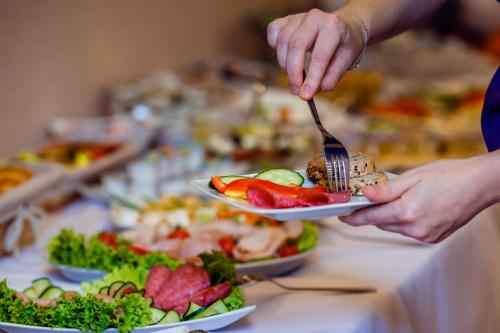 a person holding a plate of food with a fork at Boutique Hotel's II Rewolucji in Łódź
