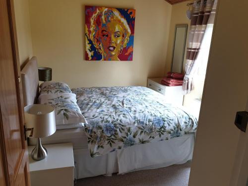 a bedroom with a bed and a painting on the wall at The Cabin,Kings Lane,Weston in Beccles
