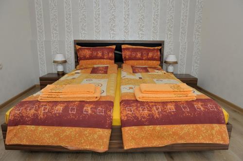 ein Schlafzimmer mit einem Bett mit orangefarbener Bettwäsche und Kissen in der Unterkunft The House of Petar Levski in Berkowiza
