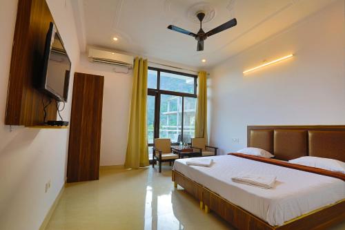 Schlafzimmer mit einem Bett und einem Flachbild-TV in der Unterkunft Hotel Tapovan Cottage in Rishikesh