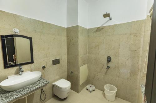 a bathroom with a sink and a toilet and a mirror at Hotel Tapovan Cottage in Rishīkesh