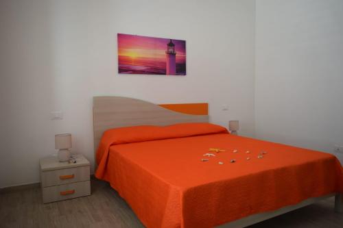 a bedroom with a bed with an orange bedspread at Acqua Chiara Appartamenti in San Vito lo Capo