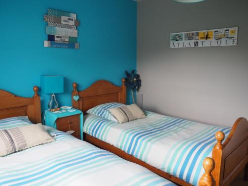 2 camas en una habitación con paredes azules en Le Clos du Carpe Diem en Cambligneul