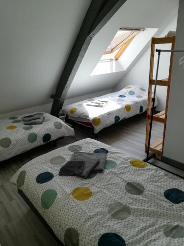 une chambre mansardée avec deux lits et une fenêtre dans l'établissement L'appart Audomarois, à Saint-Omer