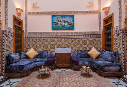 a living room with blue couches and a painting at Riad Scalia Traditional Guesthouse Fes Morocco in Fès