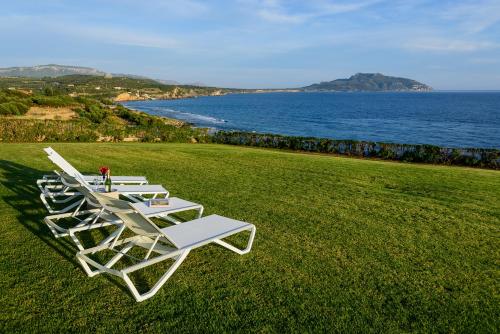 a row of lounge chairs sitting on a lawn near the ocean at Finisia House in Elia Laconias