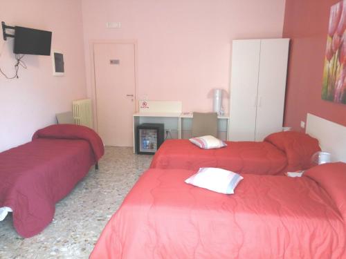 three beds in a room with red sheets at Michelangelo Rooms in Catania