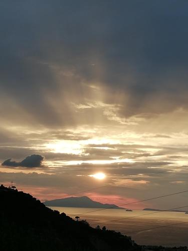 a sun setting over the water with a hill at Agriturismo L'Olivara in Piano di Sorrento