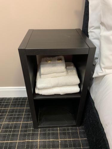 a black bedside table with towels on it next to a bed at Royal Hotel in Dingwall