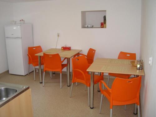 cocina con 2 mesas, sillas de color naranja y nevera en Pensiunea Sada en Cluj-Napoca