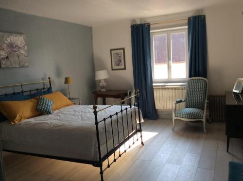 une chambre avec un lit, une chaise et une fenêtre dans l'établissement La roseraie de Camille, à Mont-sous-Vaudrey
