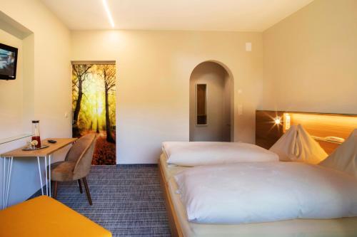 una camera d'albergo con 2 letti e una scrivania di Bed&Breakfast Pension Hilpold a Lana