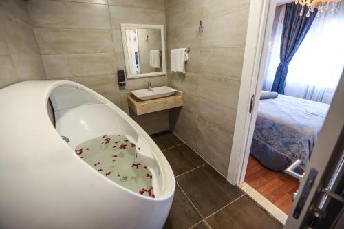 a bathroom with a tub and a sink and a bed at Thermal Saray Hotel & Yalova in Gokcedere