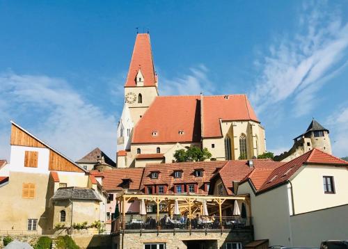 a large building with a clock tower and a church at Hotel-Restaurant Kirchenwirt in Weissenkirchen in der Wachau