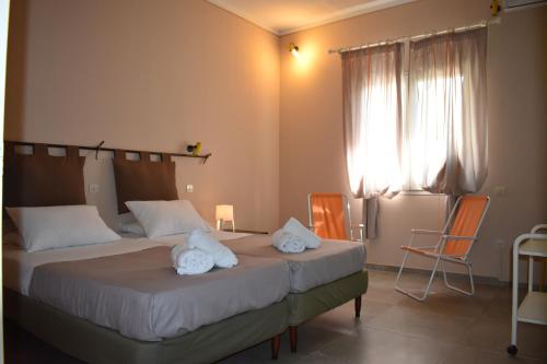 2 Betten in einem Zimmer mit 2 Stühlen und einem Fenster in der Unterkunft Korina's Apartments in Ýpsos