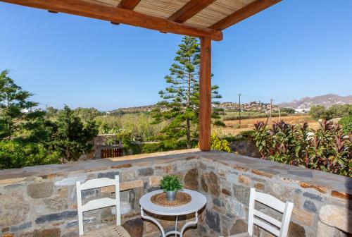 a patio with a table and chairs on a stone wall at Thea Suites Naxos in Agios Prokopios