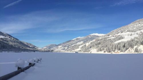 un lago cubierto de nieve con montañas en el fondo en Hofgartnerhof en Strassen