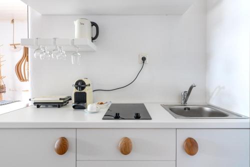 a white kitchen with a sink and a counter at Ornos Blue in Ornos