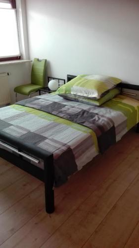 a bedroom with a bed and a green chair at Ferienwohnung nahe Ulm/Laupheim in Laupheim