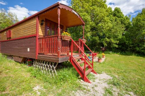 a small house with a red staircase in a field at Roulotte-Quinta La Grange d Emile in Blandas