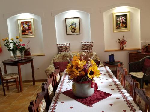 a dining room with a table with flowers on it at Pensiunea Liana in Nemşa