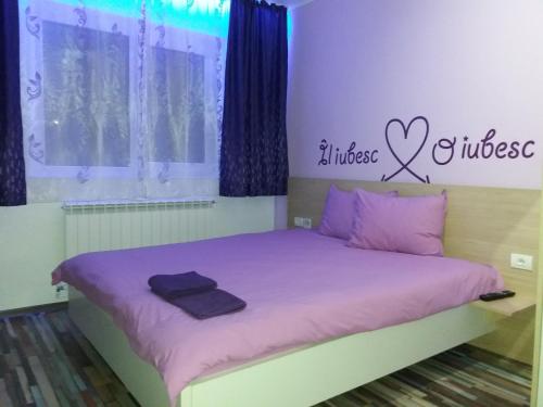 a bedroom with a bed with purple sheets and a sign at Apartament P&D in Constanţa