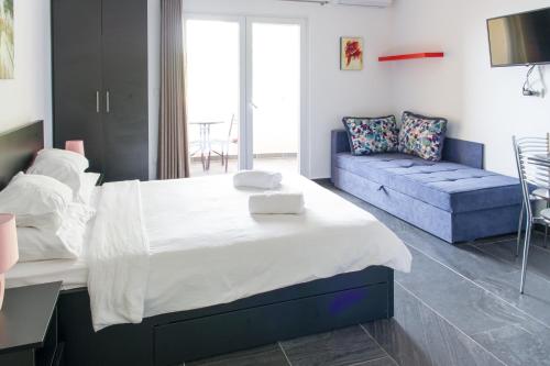 um quarto com uma cama grande e um sofá azul em Alessandra Apartments em Sveti Stefan