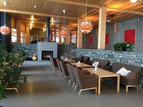 a restaurant with tables and chairs and a fireplace at Unicare Røros in Røros