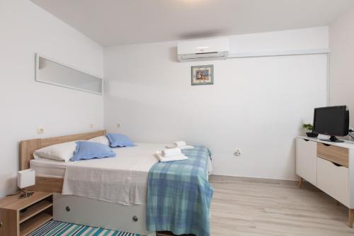 ein weißes Schlafzimmer mit einem Bett und einem TV in der Unterkunft Le Ines in Split
