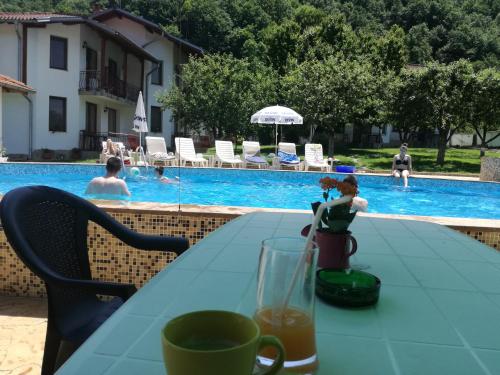 a table with a drink on it next to a swimming pool at By the River Hotel Complex in Balkanets
