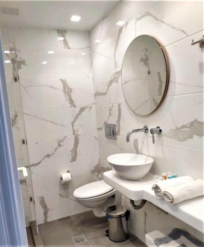 a bathroom with a toilet and a sink and a mirror at Corali Hotel in Adamantas