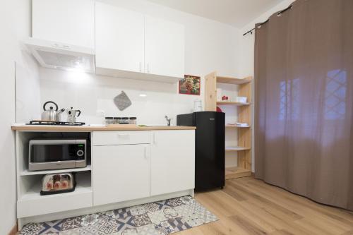 une cuisine avec des armoires blanches et un réfrigérateur noir dans l'établissement Casa Annuccia ai Quattro Canti di Città, à Palerme