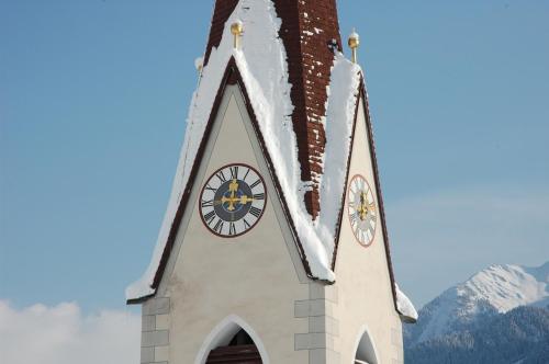 a church with a clock on the top of it at Pension Rosenegg in Finkenberg